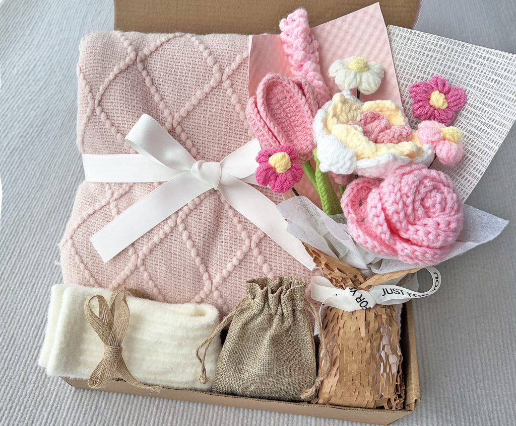Nestlygift blush pink self care gift set with diamond knit blanket, handmade crochet flower bouquet, fuzzy socks and linen pouch